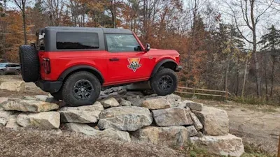 A Red 2 door Bronco on some rocks